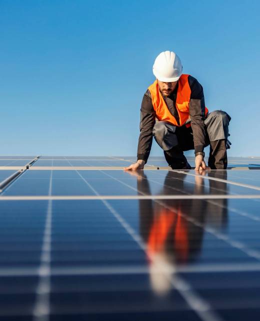 A worker installing solar panels on the roof.